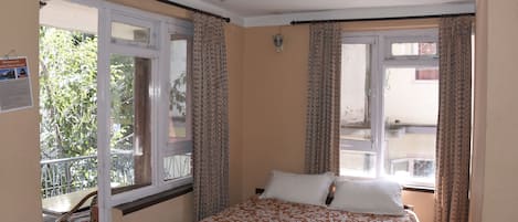 Quarto com cama, ventilador de teto e varanda com cadeira.