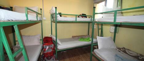 Un dormitorio con literas, suelo de madera y una ventana con cortinas.