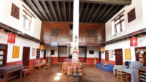 A traditional room with wooden floors, a central pillar, and a mix of seating arrangements including sofas and chairs. - Hotel Om's Home (Jomsom)