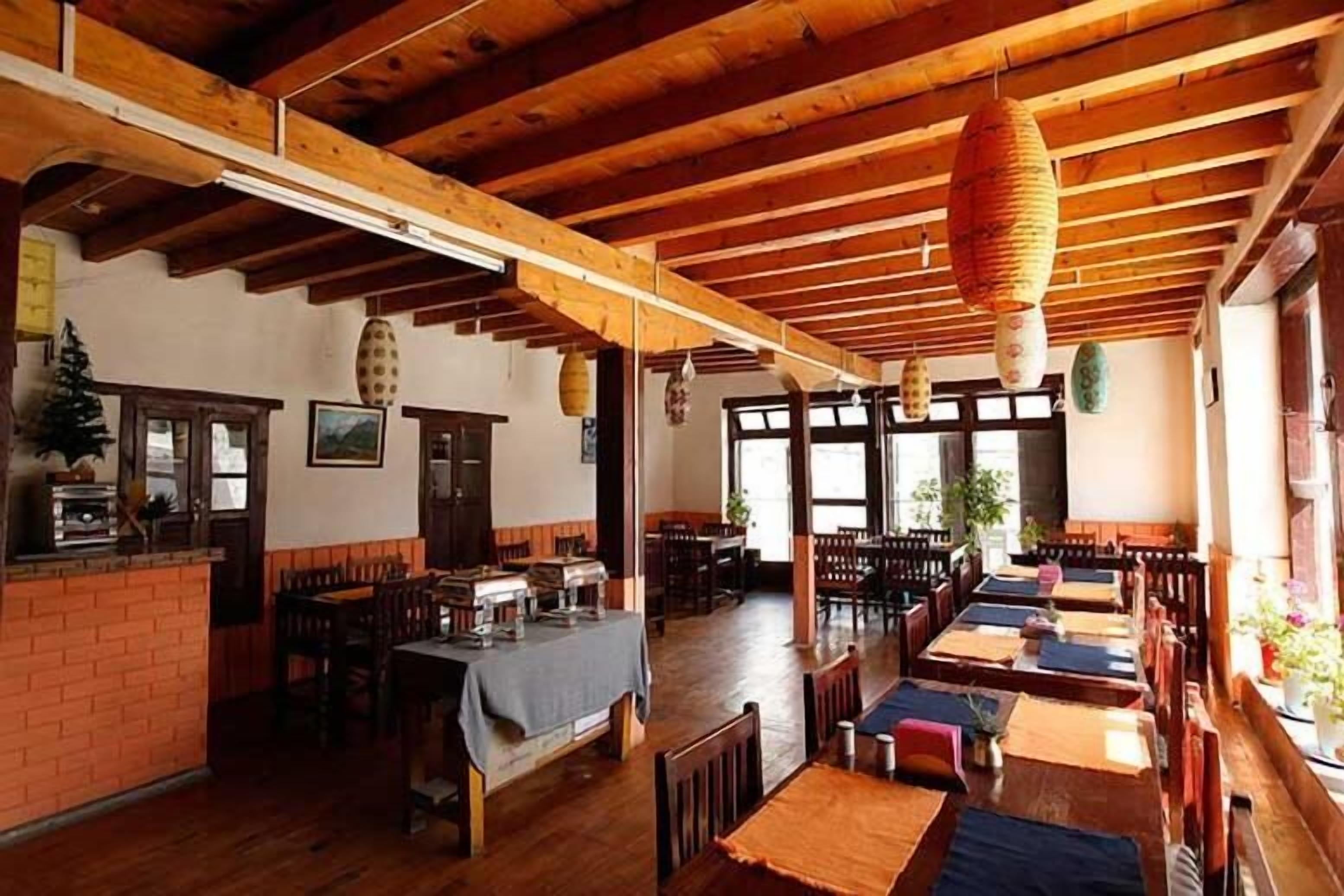 Un restaurante con vigas de madera, paredes de ladrillo y mesas dispuestas para comer.