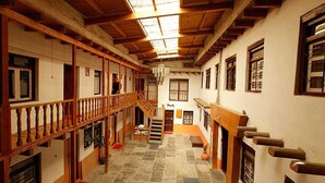 A spacious interior with a wooden staircase, a chandelier, and a view of the outside through large windows. - Hotel Om's Home (Jomsom)