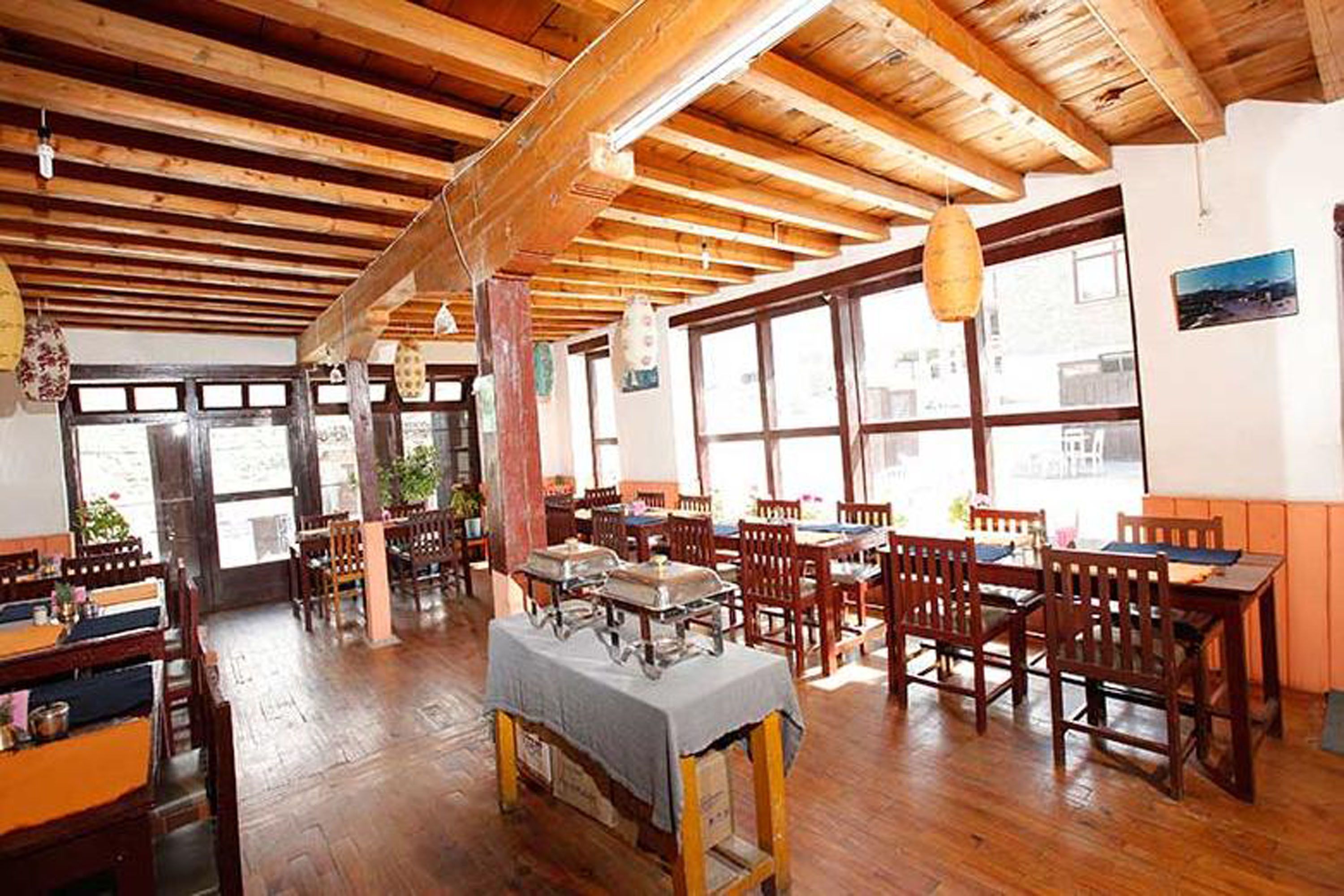Un restaurante con vigas de madera, ventanas amplias y un espacio para bufé.