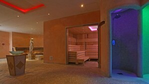Uma área de spa com sauna, mesa de massagem e piso de pedra.