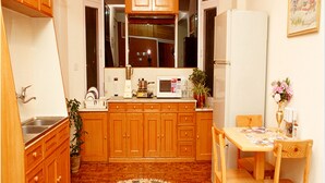Cocina compacta con armarios de madera, microondas, lavabo y comedor con mesa y sillas.