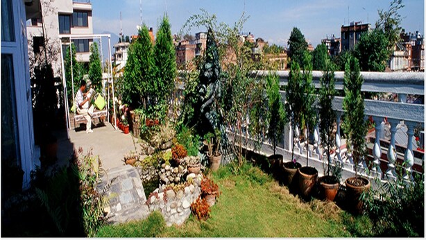 Un jardín con plantas en macetas, un muro de piedra y vistas de un río.