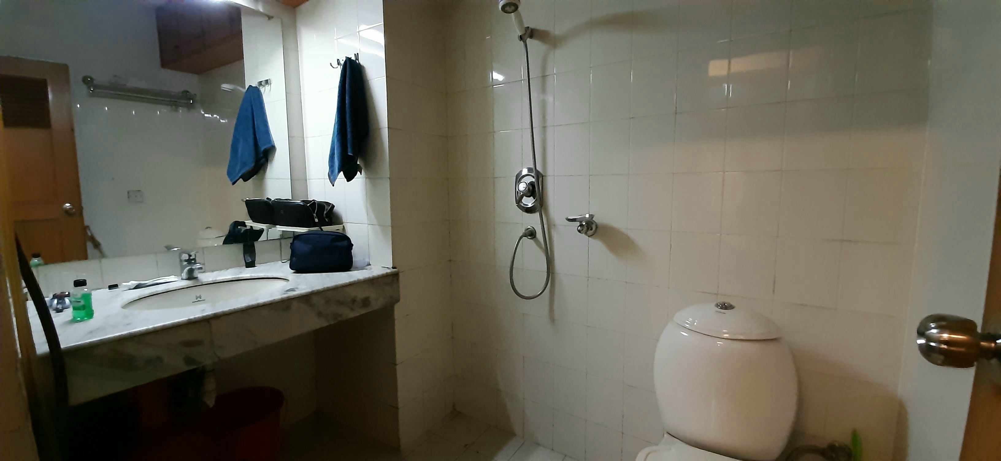 A bathroom with a sink, mirror, towel rack, shower, and toilet.