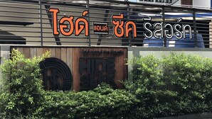 Een bord met Thaise tekst en een logo, dat een bedrijf aangeeft.