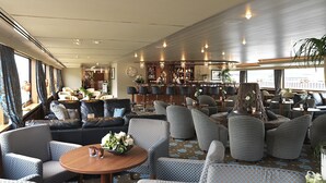A spacious lounge area with multiple seating options, a bar, and a view of the deck. - Crossgates Hotelship Hafen - Neuss (Neuss)