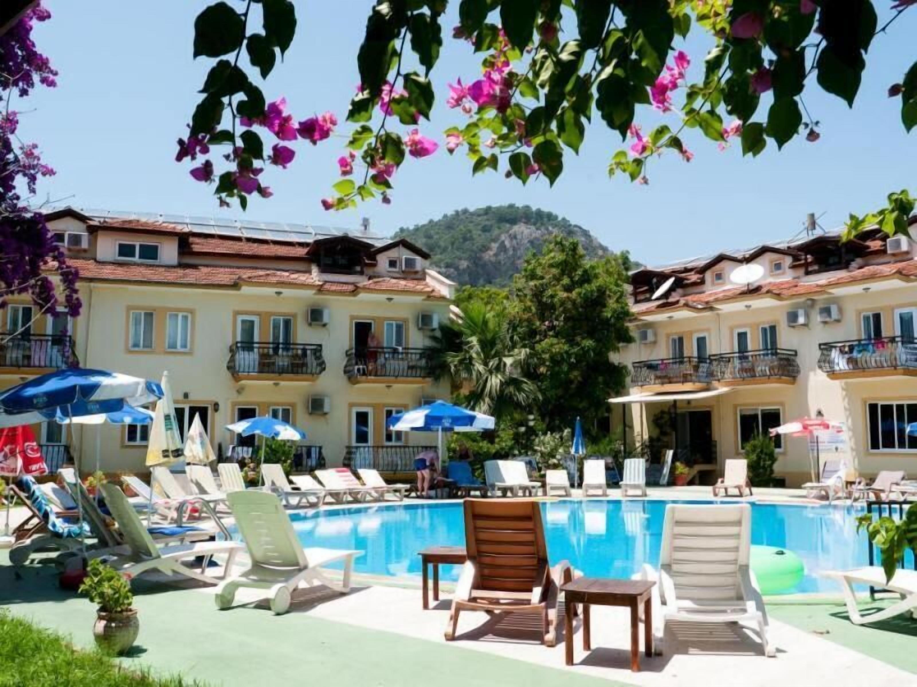 Una piscina al aire libre, sombrillas, sillones reclinables de piscina