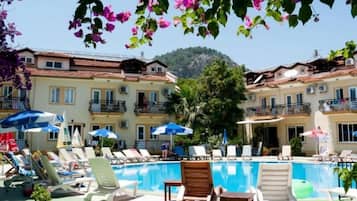 Una piscina al aire libre, sombrillas, sillones reclinables de piscina