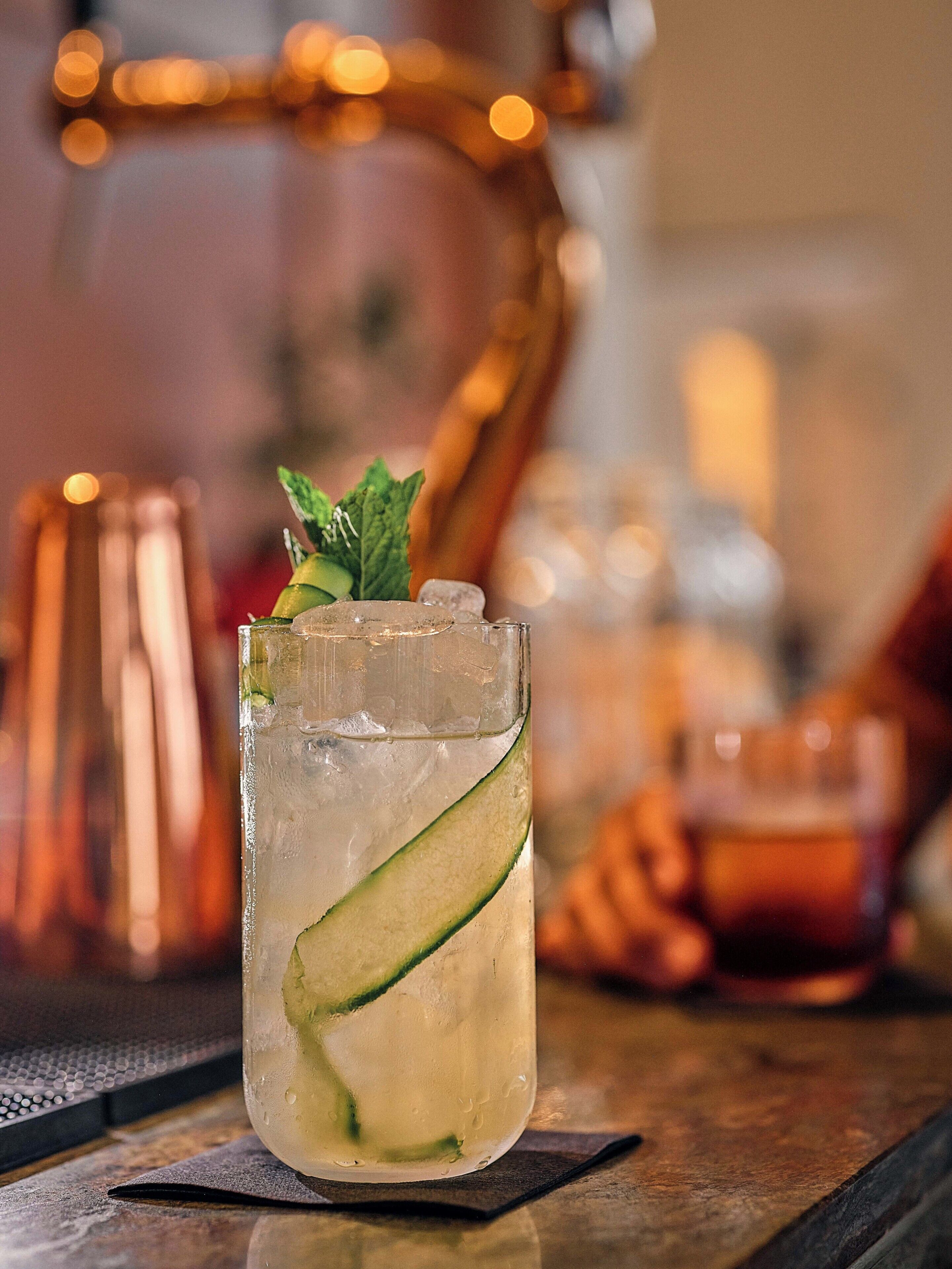 A glass with a lime slice garnish on a bar counter.