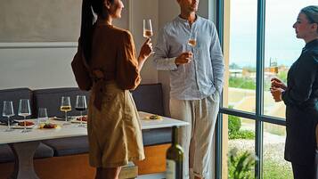 Un intérieur moderne avec un coin repas, une grande fenêtre donnant sur un beau paysage et une bouteille de vin posée sur la table.