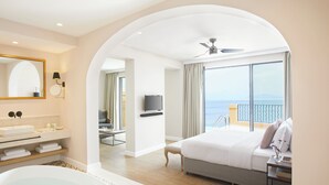 A modern hotel room with a large bed, a bathroom with a bathtub, a TV, and a balcony with a view of the sea. - Nido, Mar-Bella Collection (Corfu)