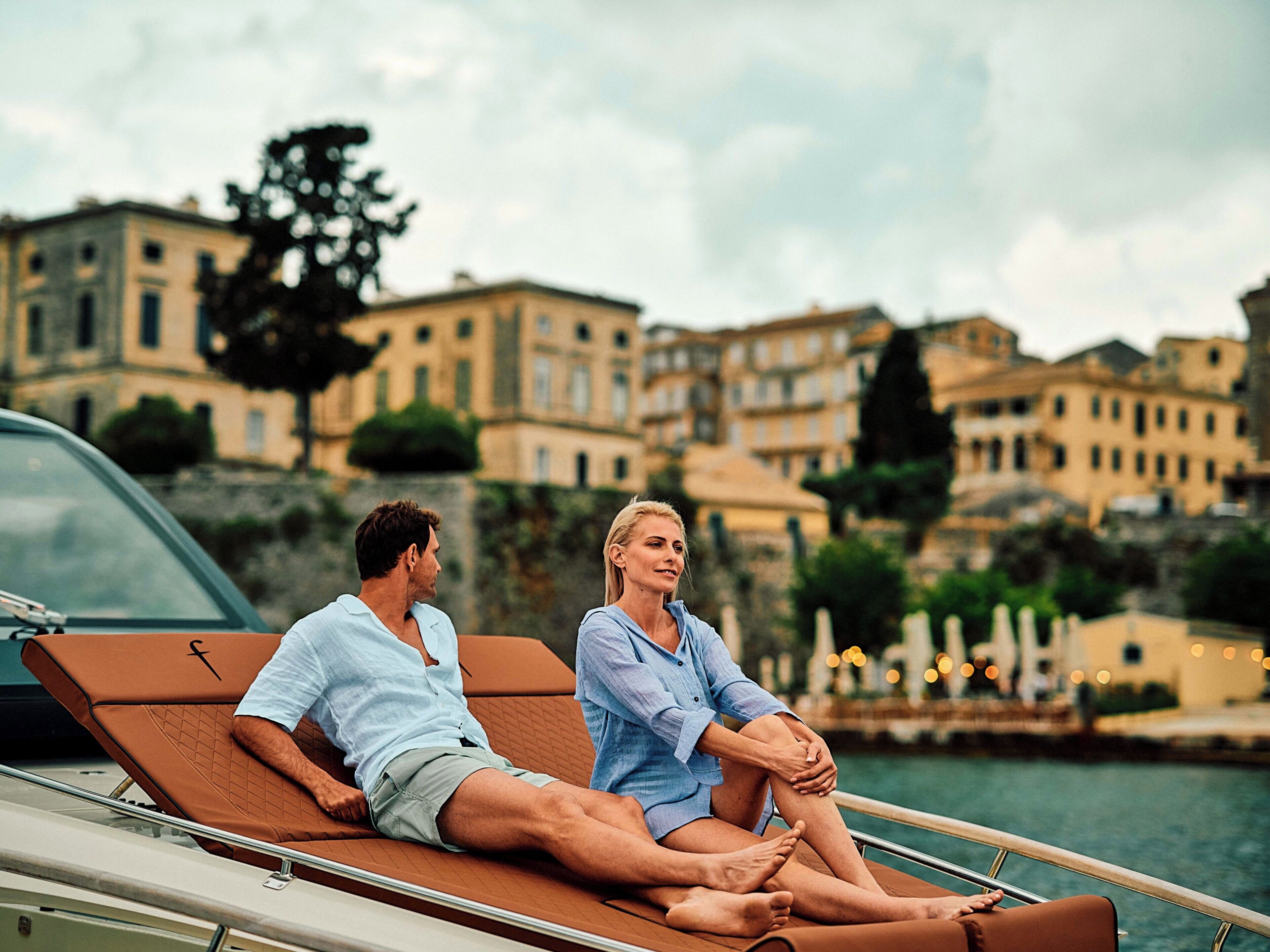 Two people sitting on a boat with a cityscape in the background.