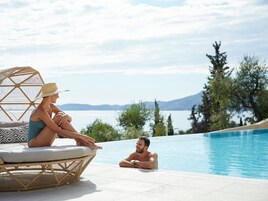Una pareja descansando junto a una piscina con vistas a un lago y montañas.
