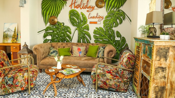 Una sala de estar acogedora con un sofá marrón, cojines verdes y una mesita de centro con revistas.
