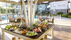 Montaje de bufé con diversas opciones de comida y vista a la piscina.