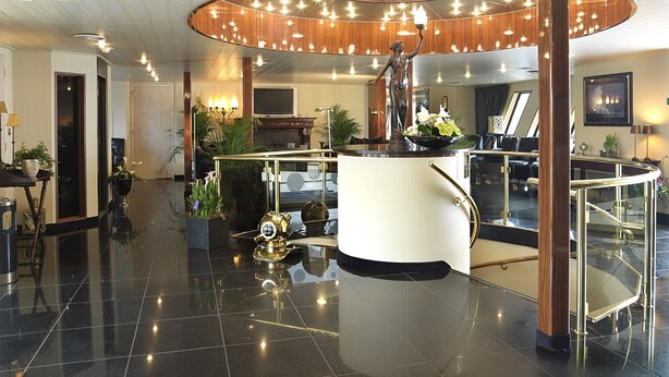 A spacious lobby with a central island, a statue, and a modern ceiling design. - Crossgates Hotelship Altstadt - Düsseldorf (Düsseldorf)