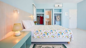 Un dormitorio con cama, mesita de noche, lámpara y una pequeña alfombra.