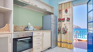Una cocina con horno empotrado, refrigerador y ventana con vista al mar.