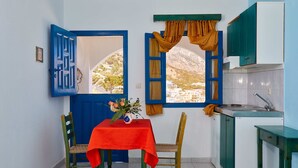 Una cocina pequeña con una ventana, una mesa con mantel rojo y una silla.