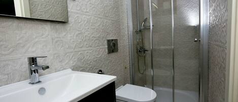 A bathroom with a white sink, a toilet, and a glass-enclosed shower.