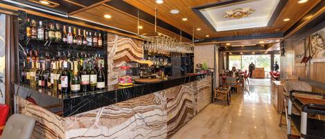 A bar area with a marble countertop, wooden ceiling, and various bottles and glasses.