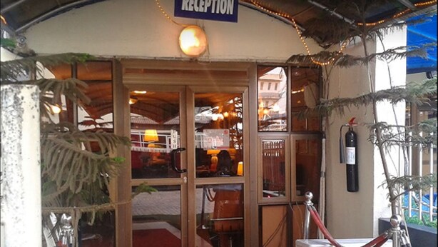 Un'area reception con un cartello, una ventola e un estintore.