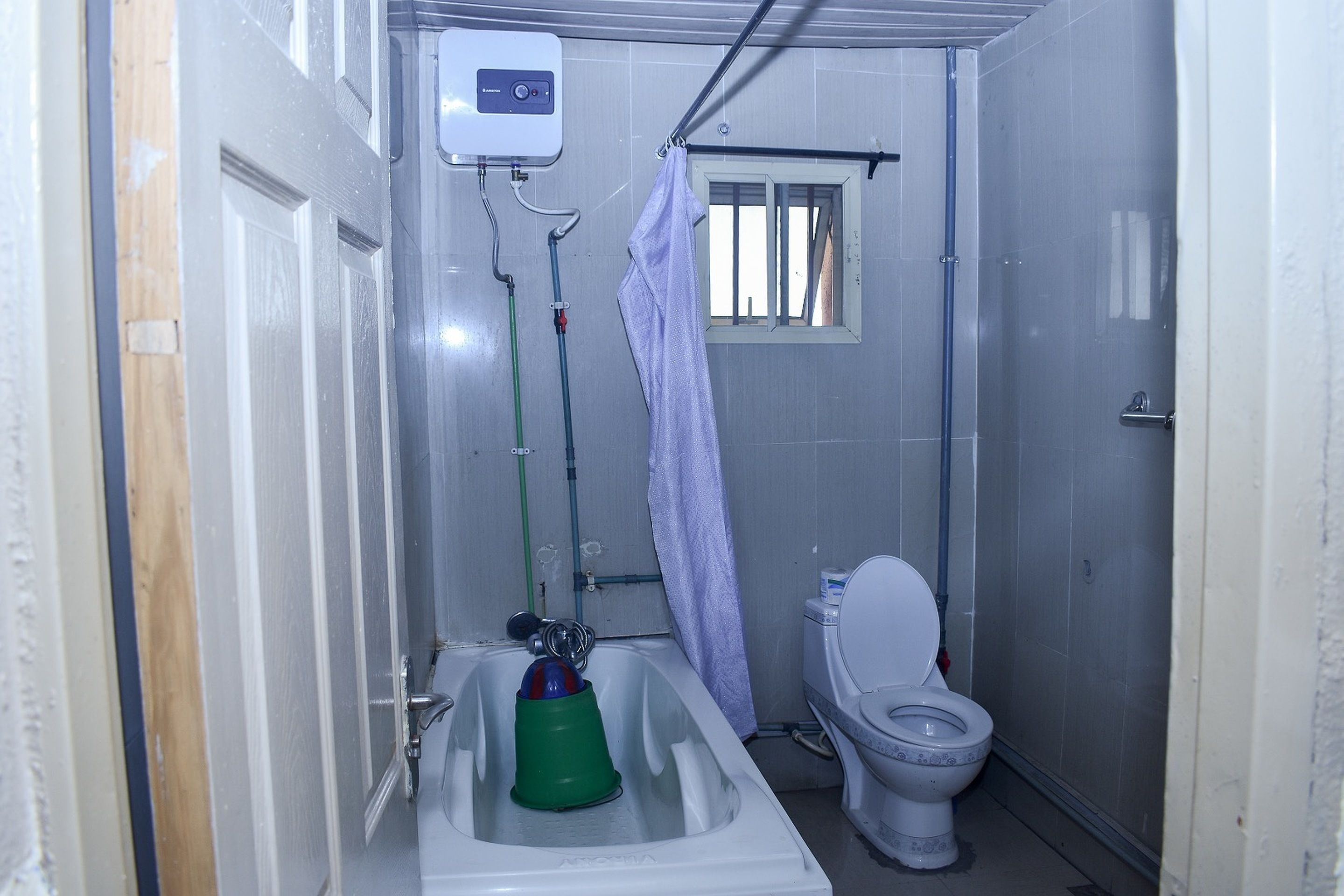 Un baño pequeño con inodoro, ducha y calentador de agua.