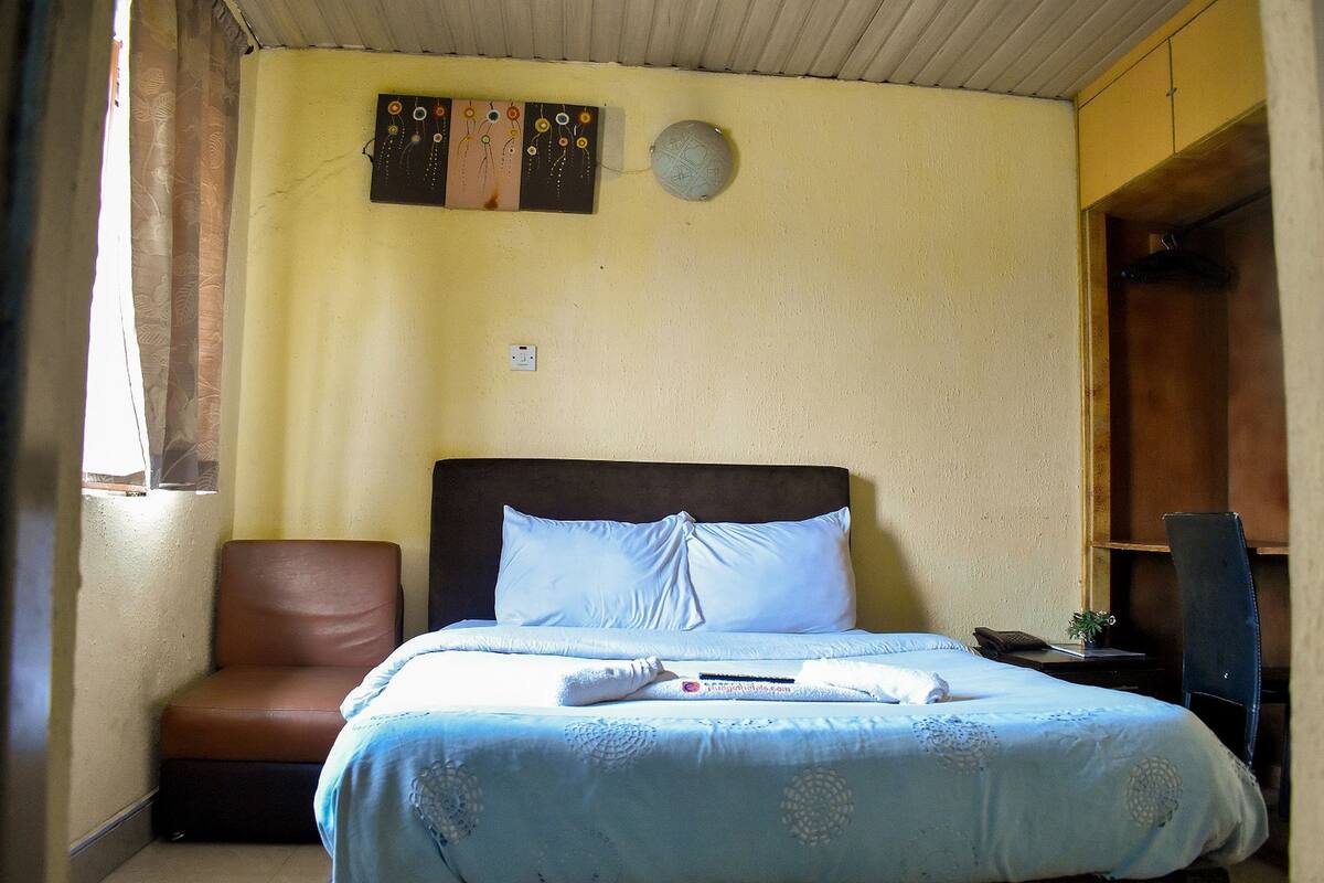 Une chambre à coucher avec un lit, une chaise, un bureau et une armoire.