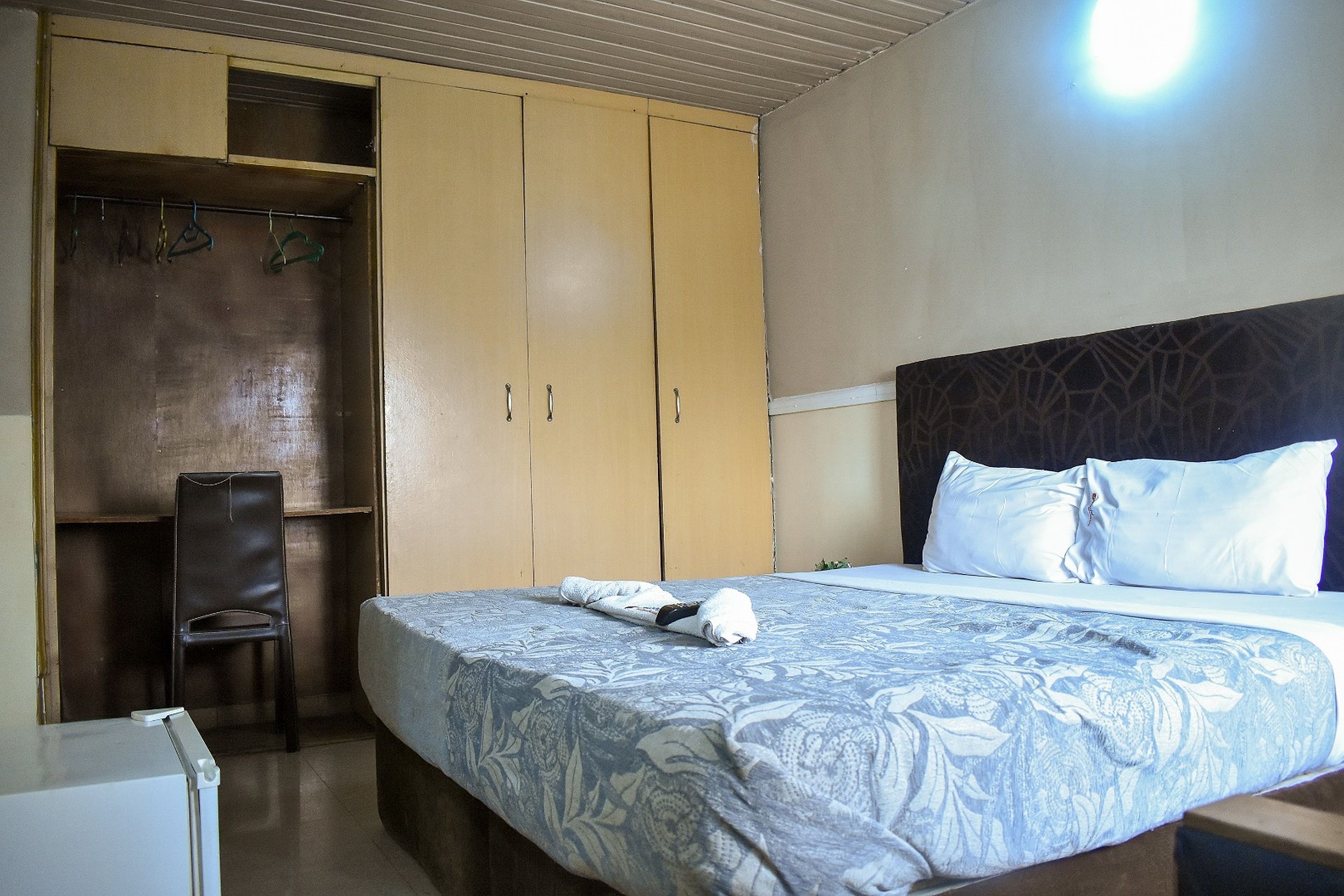 A bedroom with a bed, a chair, and a wardrobe.