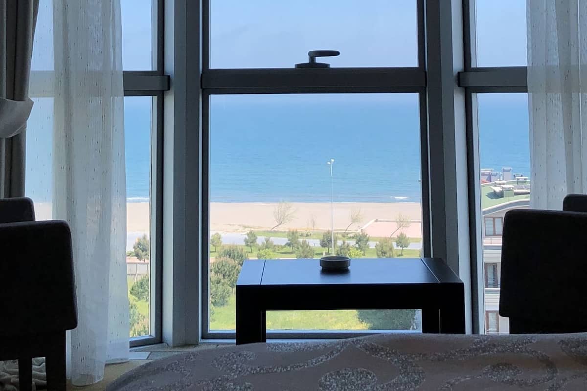 A bay window with a view of the sea, a small table, and two chairs.