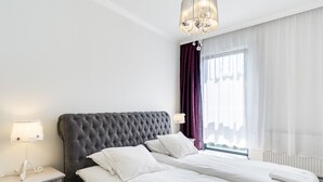 A hotel room with a large bed, a nightstand, a lamp, and a window with curtains.