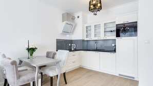 A modern kitchen with white cabinetry, a grey countertop, and a chandelier.