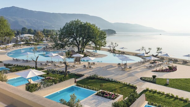 Un resort con varias piscinas, zonas de descanso y vistas al mar y a las montañas.
