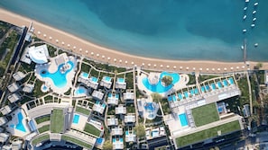 Vista aérea de un complejo turístico con varias piscinas, una playa y un muelle.
