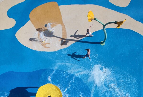 A water park with a large pool, slides, and a yellow play structure.