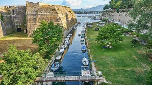 A historic fort with a moat, boats docked along the water, and a grassy area with a small bridge.