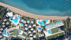 Vista aérea de un complejo turístico con varias piscinas, una playa y un muelle.