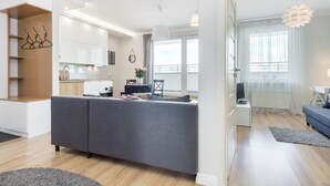 Een moderne woonruimte met een grijze bank, een eethoek en een keuken.