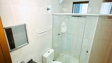 A bathroom with a white toilet, a sink, and a glass shower enclosure.