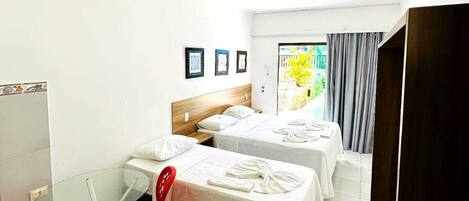 Habitación de hotel con dos camas, una mesita de vidrio, sillas rojas y vista al exterior.