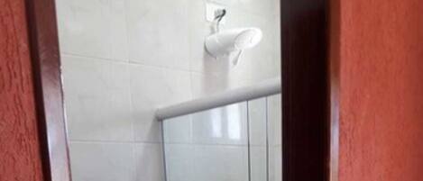 A small bathroom with a toilet, a glass shower enclosure, and a white sink.