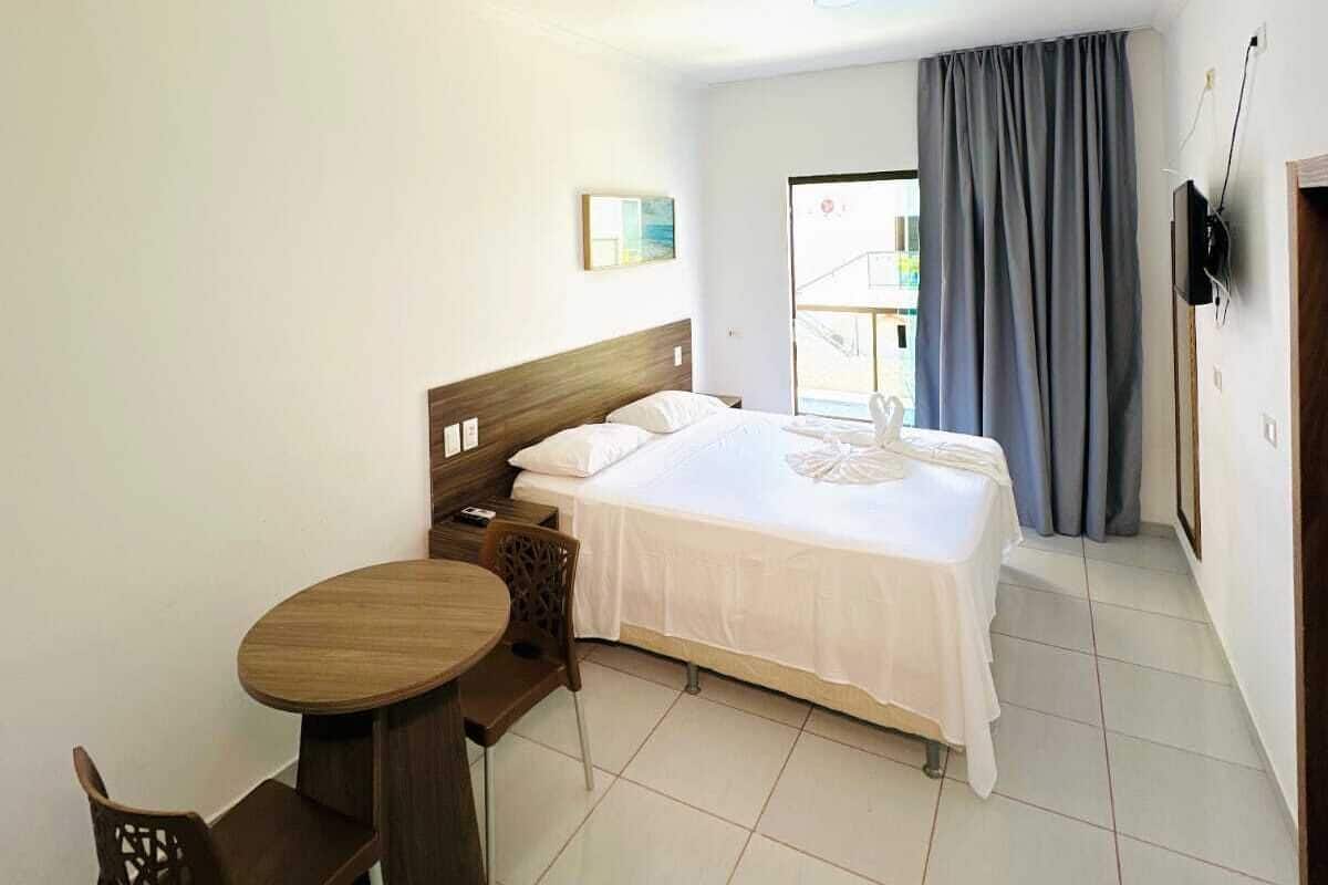 A hotel room with a bed, a small table, and a chair.