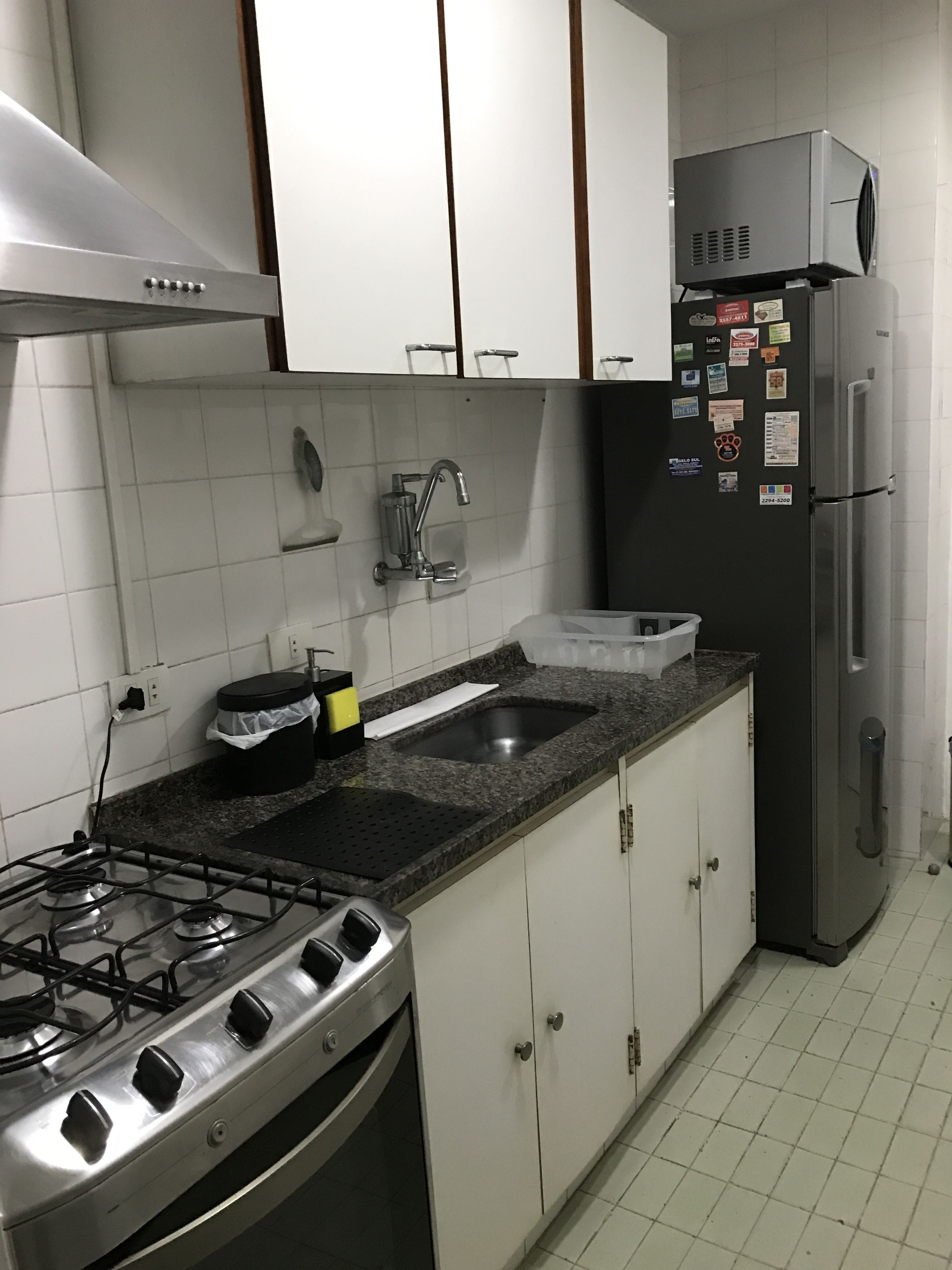 Una cocina con estufa a gas, refrigerador de acero inoxidable y gabinetes blancos.