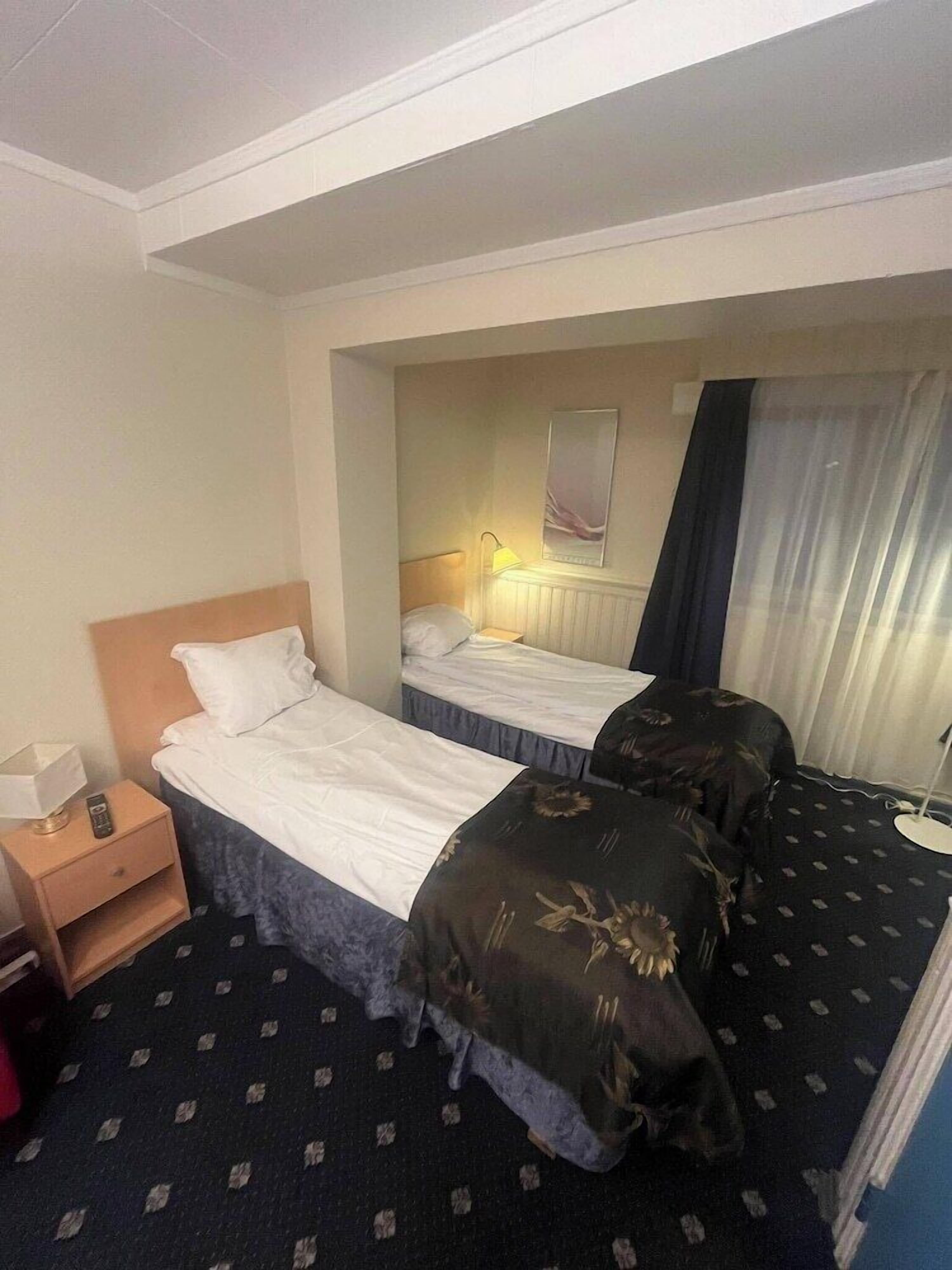 Une chambre d’hôtel avec deux lits, une table de chevet, une lampe et un miroir.