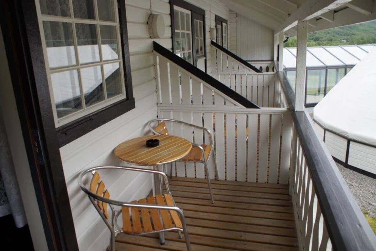 A wooden deck with a table and chairs, a staircase, and a white railing.