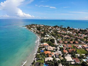 An aerial view of a coastal residential area with houses, a beach, and a clear sky. - Pousada Santo Aleixo (Ipojuca)