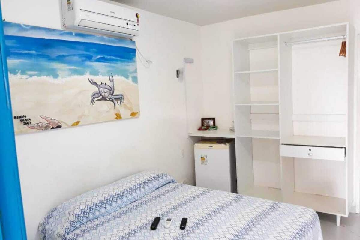 Quarto com cama, escrivaninha, frigorífico e guarda-roupa.