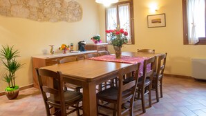 Un comedor con una mesa y sillas de madera, una pared de piedra y una lámpara colgante.